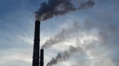 Sanayi kenti üzerinde gün batımı. Fabrika bacaları tütüyor. Çevresel çevre ve atmosfer kirliliği sorunu. İklim değişikliği, çevre felaketi.