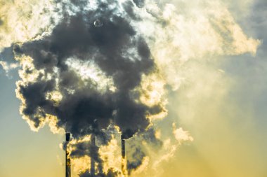 Sanayi kenti üzerinde gün batımı. Fabrika bacaları tütüyor. Çevresel çevre ve atmosfer kirliliği sorunu. İklim değişikliği, çevre felaketi.