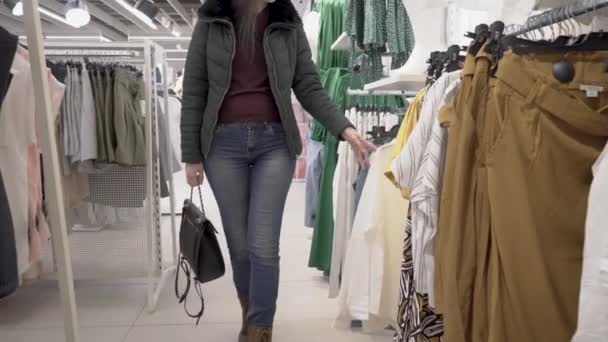 俄罗斯莫斯科04 2021 女人们的手在服装店甩卖的衣橱的衣架上选择时髦的衣服和服装 — 图库视频影像