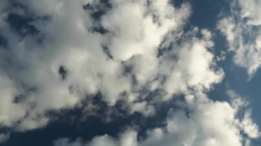Mavi gökyüzü ve beyaz tüy bulutları. Mavi gökyüzünün hareketli panoramik görüntüsü. Baş döndürücü bir video. Açık gökyüzü ile güzel bir hava.