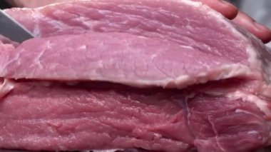 Masaya yakın plan bıçakla domuz eti ya da sığır eti kes. Et tabakları ve yemek hazırlığı. Kırmızı et parçaları..