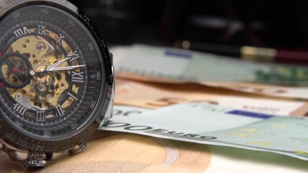 時間はお金です クローズアップの美しい機械式時計は ユーロのお金にあります ユーロ銀行券の手動カウント ユーロ紙幣 ヨーロッパでの現金の歴史 ヨーロッパの銀行券は 接線政策です — ストック動画