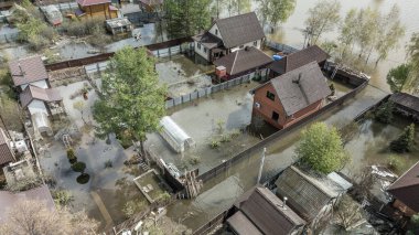 Büyük bir şehrin su altında evleri ve caddeleri olan insansız hava aracı görüntüleri. Şiddetli hava ve sağanak yağış kaynaklı kentsel sel, yerleşim alanları üzerinde doğal afet etkisi gösteriyor. İklim değişikliği