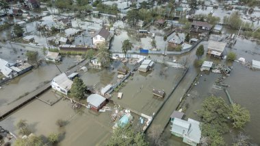 Büyük ölçekli bir sel felaketi. Tamamen sular altında kalmış evler, sular altında kalmış yollar ve taşmış su yolları. Görüntüler şiddetli yağış ve yükselen su seviyelerinin yerleşim alanları, altyapı ve doğal çevre üzerindeki dramatik etkisini gösteriyor..