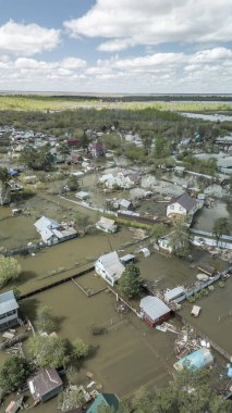Büyük ölçekli bir sel felaketi. Tamamen sular altında kalmış evler, sular altında kalmış yollar ve taşmış su yolları. Görüntüler şiddetli yağış ve yükselen su seviyelerinin yerleşim alanları, altyapı ve doğal çevre üzerindeki dramatik etkisini gösteriyor..