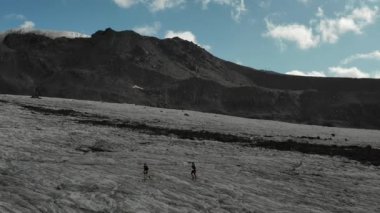Elbrus bölgesindeki Buzul 'da koşan bir grup insan üzerinde havadan uçuş.