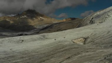 Elbrus bölgesindeki Buzul 'da koşan bir grup insan üzerinde havadan uçuş.