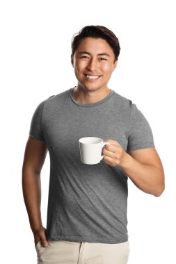 Attractive smiling asian man wearing a grey t-shirt holding a mug. Standing against a white background.