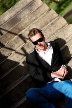 Genç adam oturma aşağı dışarıda