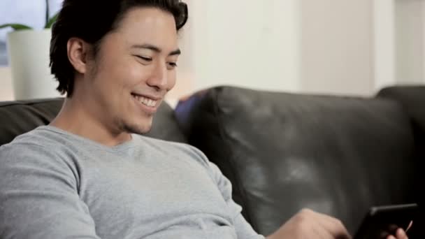 Чоловік сидить у вітальні, витираючи свій цифровий планшет — стокове відео