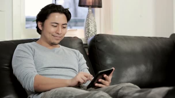 Man sitting down in living room swiping his digital tablet — Stock Video