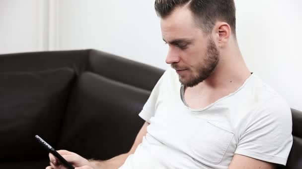 Hombre joven en una camiseta con una tableta digital — Vídeos de Stock