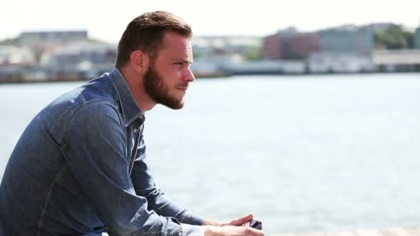 Homem sentado ao ar livre perto da água — Vídeo de Stock