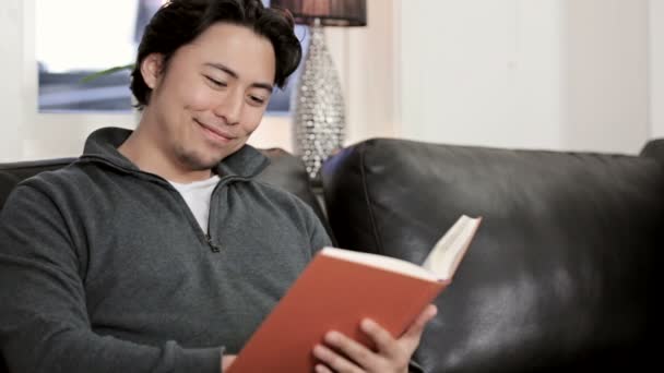 Az ember élvezi egy jó könyvet otthonában — Stock videók