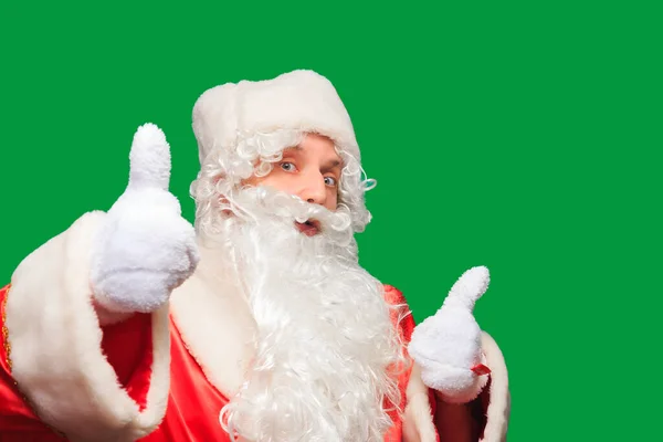 Young men dressed in Santa Claus costume with thumb up sign isolated on green background — Stock Photo, Image