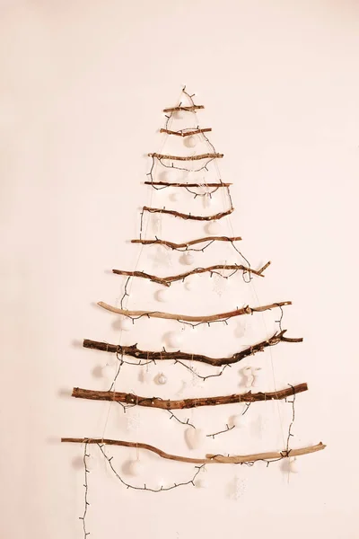 Висит на стене альтернативная деревянная елка с деревянными украшениями. Стоковая Картинка