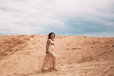 Çöldeki kumların kumlarında yürüyen bir kadın çöl kumlarında yürüyen, parlak bir yaz gününde beyaz kumda yürüyen genç bir kadın.