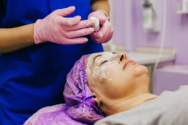 Cosmetólogo Está Aplicando Crema Con Anestesia Cara Del Paciente Vista Fotos de stock