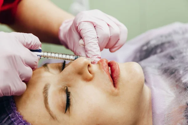 Женщина получает инъекцию гиалуроновой кислоты в качестве кожного наполнителя для увеличения губ Стоковое Изображение