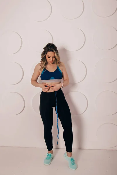 Woman measuring her waist with centimeter tape at home. Fast weight loss concept.