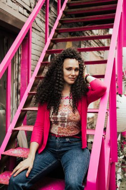 Kıvırcık saçlı, pembe hippi kıyafetleri giymiş güzel bir manken..