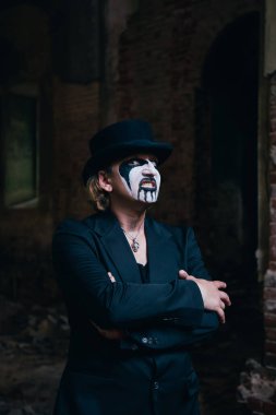 Korkunç Cadılar Bayramı makyajlı, silindir şapkalı korkunç bir adam karanlık köşeden çıkıp korkutmaya çalışıyor. Korku teması.