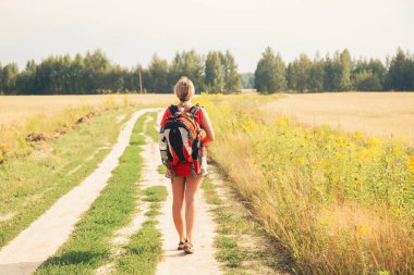 Doğa yürüyüşü yapan genç bir kadın. Mutlu kız kamp çantalarıyla orman yolunda yürüyor. Ormanda bir gezgin. Seyahat özgürlüğü yaşam tarzı