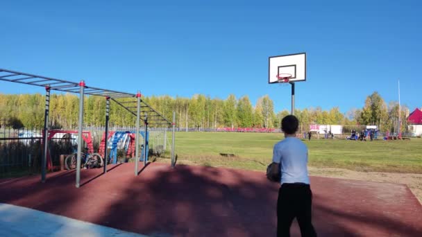 Adolescente na rua joga basquete e bate o aro. Adolescente em jogo de verão — Vídeo de Stock