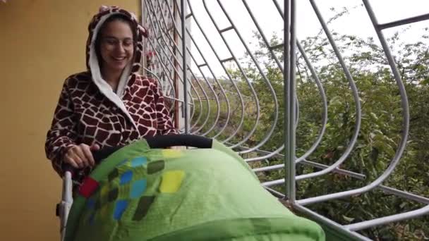 Anya nevet zsiráf rugdalózó baba babakocsi az erkélyen zárlat alatt — Stock videók