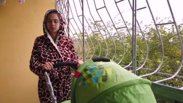 Moeder met giraffe onesie met baby in kinderwagen op balkon tijdens lockdown — Stockvideo