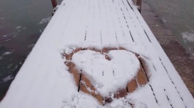Kar limanında kalp şeklinde kar taneleri düşüyor ve sert hava var.