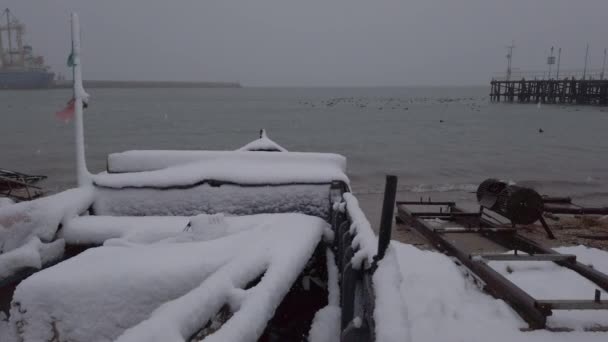 Loď na rybářské vesnici během zimního sněhu. Vzácné pohledy na sníh na mořském břehu. — Stock video