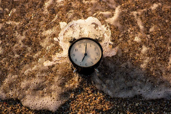 Relógio de alarme salpicando na água da praia — Fotografia de Stock