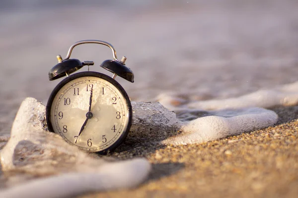 Reloj despertador salpicando en el agua de la playa — Foto de Stock