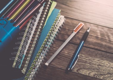 Defter kalemler üzerinde ahşap masa ile yığını