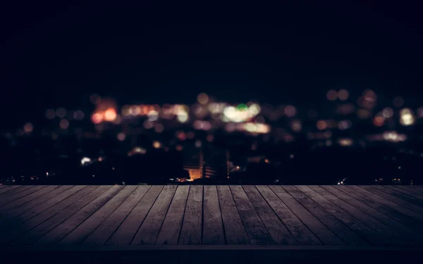 Houten plank boven de stad bij nacht — Stockfoto