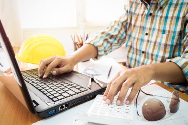 Hesap makinesi ve inşaat pla ile dizüstü bilgisayar üzerinde çalışan mimar