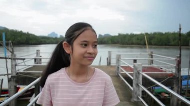 Mutlu Asyalı genç kız Phang Nga Koyu 'ndaki iskelede sakin bir şekilde yürüyor ve güzel manzaraları seyrediyor. Seyahat güzergahı. Tayland.
