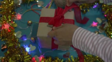 Kadın elleri Noel ve Yeni Yıl konsepti için hediye kutusunda kırmızı kurdeleyi açıyor. Mutluluk festivali özel bir hediyeyle.