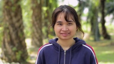 Mavi ceketli Asyalı sevimli kızın portresi sabah yağ palmiyesinin arasında dururken gülümsüyor. Mutlu Taylandlı genç kız güneş ışığı altındaki kırsal bölgede kameraya bakıyor. Sağlıklı yaşam tarzı.