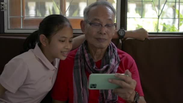 Urocza Wnuczka Podchodząca Siedząca Obok Swojego Dziadka Oglądająca Media Społecznościowe — Wideo stockowe