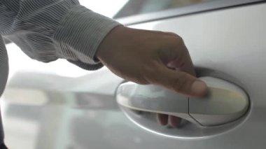 Bir adamın açtığı arabanın arka kapı koluna yakın çekim. Asyalı işadamı bir araca atlayıp kapıyı kapatıyor.. 