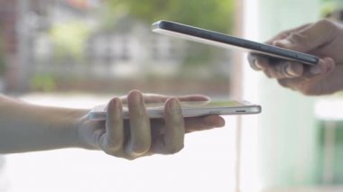 Çevrimiçi ürün ücreti için QR kod ödemelerini taramak için akıllı telefon kullanarak insanların elini kapat. Kurye kadın, erkek müşteriye göndermek için kağıt torba tutuyor. Teslimatı evde yapın..
