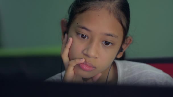 自宅のノートパソコンから授業をオンラインで勉強しながら 講師の話を熱心に聞いているイヤホンをつけているアジア系の中学生 遠隔教育 — ストック動画