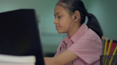 Kulaklık takan sevimli genç bir kız evdeki bilgisayar kamerasıyla öğretmenine ev ödevini açıklıyor. Uzaktan eğitim. Liseli kız video çalışması için laptop kullanıyor.. 