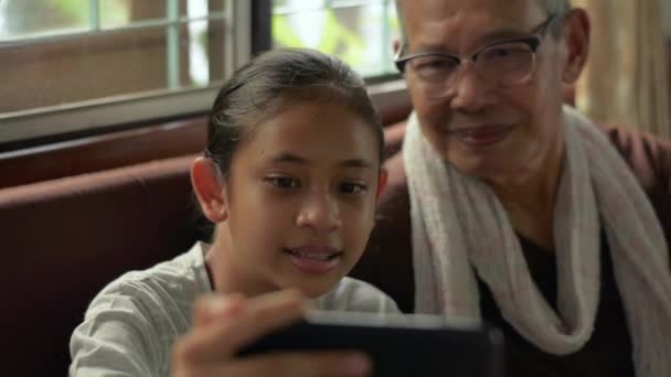 快乐的亚洲漂亮孙女和她的祖父喜欢通过家里的智能手机摄像头在网上通过视频通话与家人交谈 与移动电话技术的远程通信 — 图库视频影像