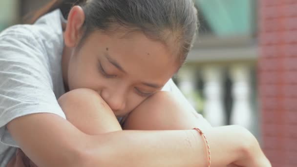 悲伤的亚洲漂亮女孩一个人坐着 在家里被隔离时闭上眼睛 紧闭忧郁症少女的脸庞靠在膝头上 — 图库视频影像
