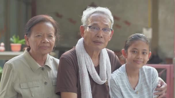 与可爱的孙女坐在一起 在家里看着相机的快乐健康的老年退休祖父母的画像 两代人的团结 亚洲家庭生活方式 — 图库视频影像