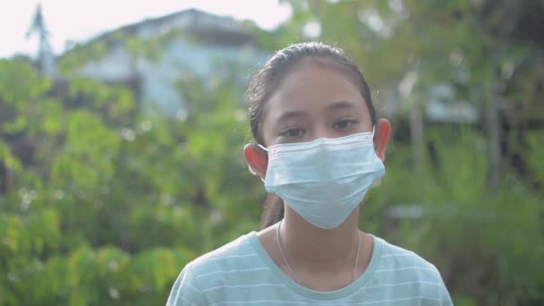家の外に滞在中にウイルスの拡散を防ぐためにフェイスマスクを身に着けているかなりタイの女の子 Covid 19流行時の安全のために練習保護マスクの女性ティーン — ストック動画