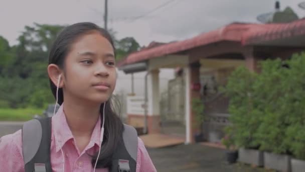 아시아의 머리에 배낭을 여대생은 거리를 하게걸어 집으로 이어폰을 학교로 돌아가 — 비디오